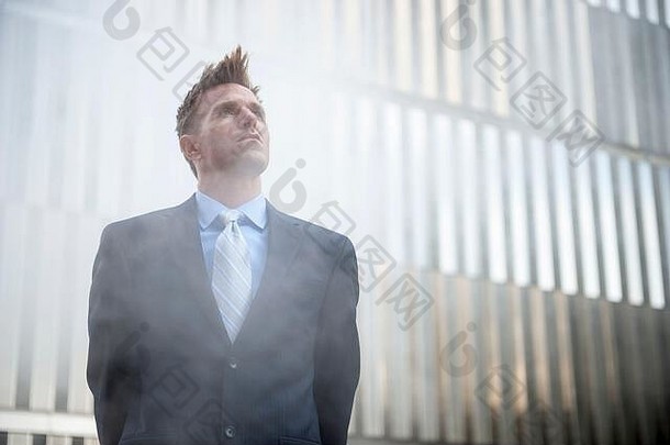 商人站在室外的蒸汽云中，站在闪亮的摩天大楼背景前