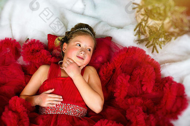 小冬公主戴着一顶珍贵的王冠，穿着红色衣服，躺在人造雪上。欢迎<strong><strong>新</strong>年</strong>和圣诞节