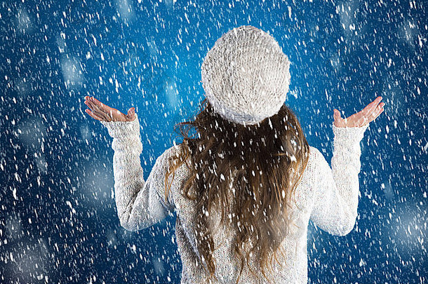 美丽的女人穿着温暖的毛衣，蓝色背景上有雪花环绕