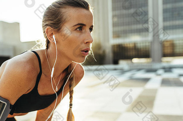 女运动员放松锻炼站在户外健身女人练习在户外听音乐穿耳机