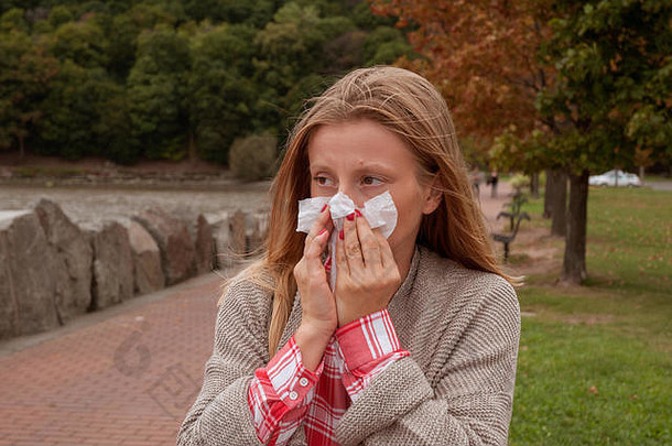 妇女患感冒或流感。那个女孩在公园里感冒了