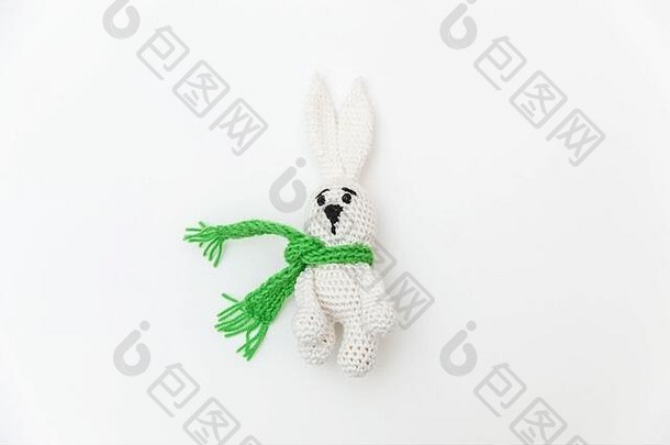 简单简约的设计，白色背景上隔离着绿色围巾的玩具兔子。儿童保育材料家庭观念。平面俯视图空间