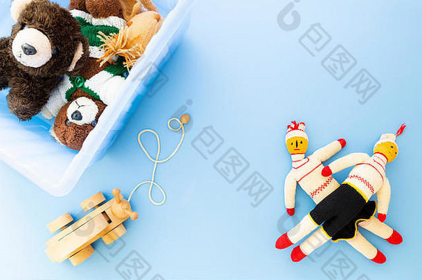 蓝色背景上蓝色塑料盒中有趣的复古儿童玩具俯视图。产品组合包括一只松鼠、一只泰迪熊、玩具娃娃和一只木制玩具