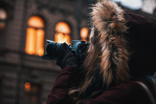 赶时髦的人女孩旅行者专业相机走晚上城市街采取照片
