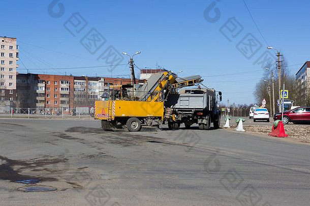 春天，在五条道路的十字路口，一辆带黄色拖车的城市清扫车用一把圆形刷子清扫道路上的污垢。中国，俄罗斯，报告文学。