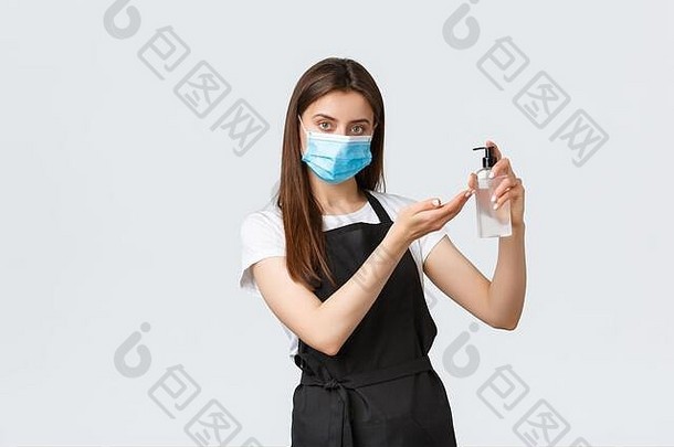 2019冠状病毒疾病，咖啡店和冠状病毒的概念。面容严肃的出纳，穿着黑色围裙和医用口罩的咖啡师