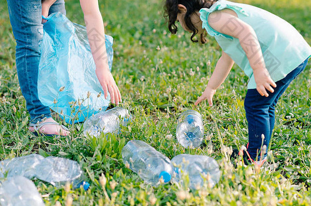 孩子们在公园里打扫卫生。双手合拢，<strong>志愿者</strong>带着垃圾袋垃圾，把塑料瓶放在回收袋里。