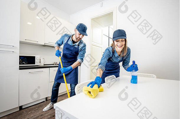 男人。女人专业清洁工统一的洗地板上擦拭家具白色厨房清洁服务概念