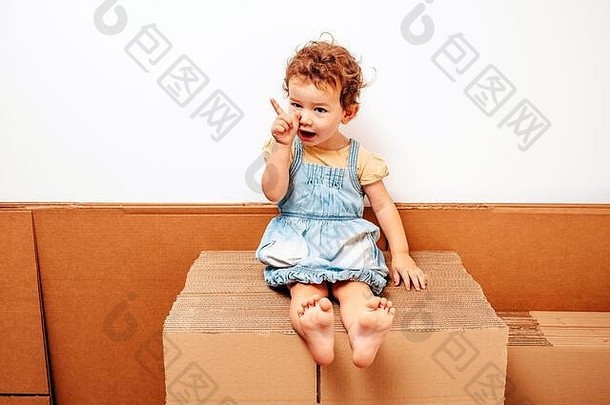 女孩独自在纸板箱上玩，表情滑稽。