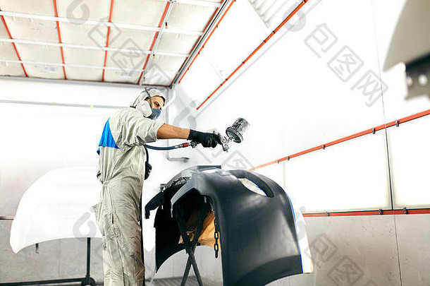 工人在专用车库油漆汽车零件，穿着服装和防护装备