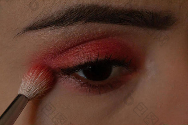 年轻的女人把化妆眼睛明亮的粉红色的眼睛影子化妆刷