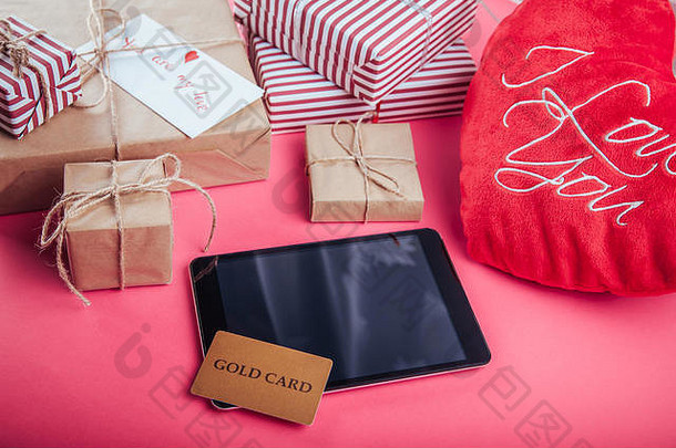 用金卡为情人节买礼物。粉红色背景上的礼品盒和心形枕头