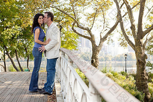 一个男人在桥上的公园里亲吻一个女人