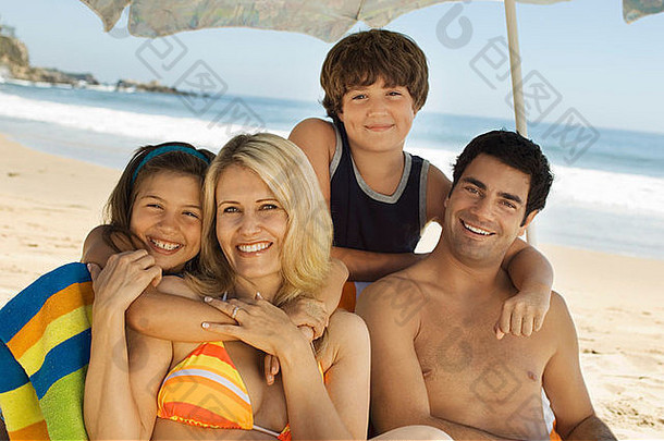 家庭泳装坐着海滩肖像
