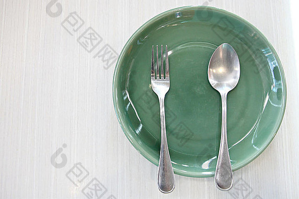 桌子上的绿色盘子和勺子。