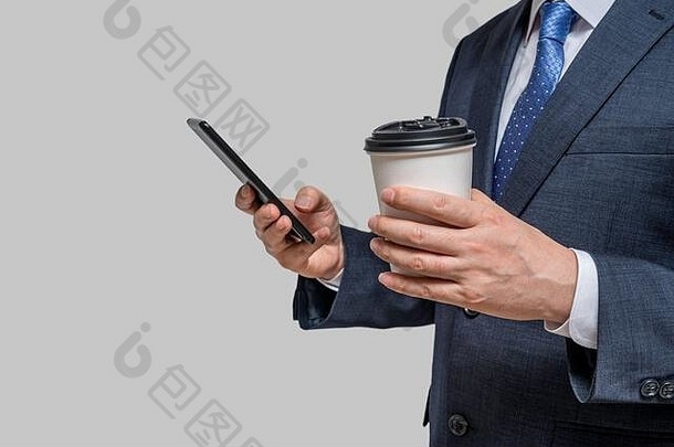 一个商人拿着一个白色<strong>纸杯</strong>和一部智能手机。使用拷贝空间。