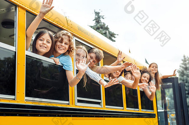 坐公交车上学的同学们斜靠在窗外，微笑着向镜头挥手