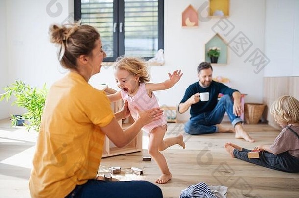 一个年轻的家庭带着两个小孩在卧室里玩耍。