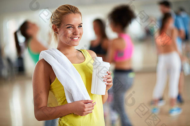在健身中心用毛巾和一瓶蛋白质饮料训练后的年轻金发女子