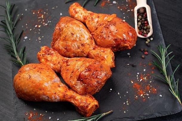生腌制鸡腿，用于烧烤和烧烤。白色盘子上的红色腌鸡腿。顶视图。鸡肉特写。。食用肉。烹饪