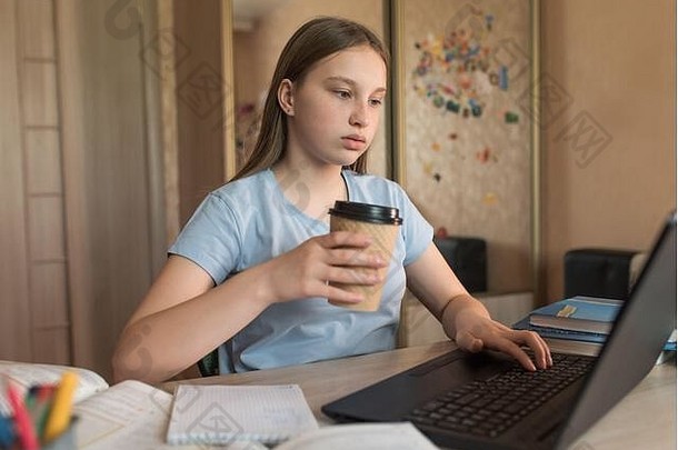 少女手里拿着一杯咖啡茶，小吃，看视频互联网社交网络，家庭电子教育休闲，笔记本电脑，远程视频