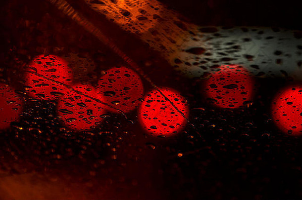 雨天透过挡风玻璃看到的城市交通夜间灯光。城市夜景的抽象背景与灯光背景。城市夜生活与汽车的概念