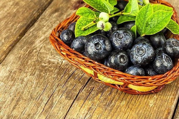 把蓝莓放在一个小柳条篮子里。在木桌<strong>上新</strong>采摘的森林水果。蓝莓的销售。健康<strong>夏日</strong>点心