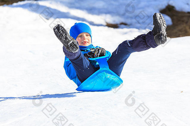 男孩骑着一辆小雪橇，微笑着，以最快的速度前进