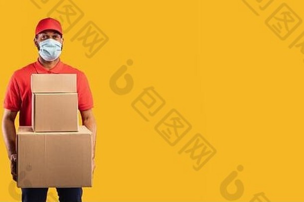 非洲送货员戴着面具拿着箱子，黄色背景，全景