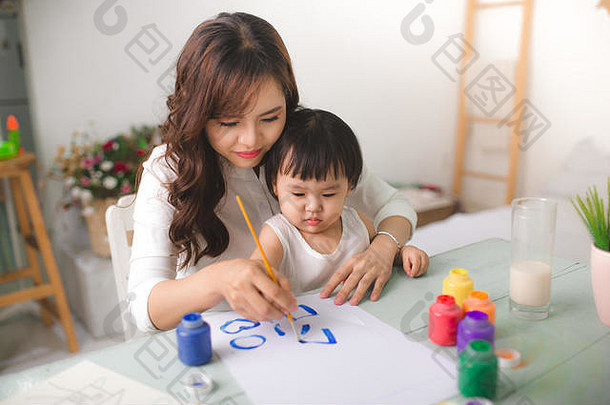 快乐家庭妈妈。女儿油漆亚洲女人帮助孩子女孩