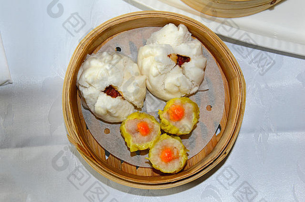 点心、饺子和中国小圆面包放在竹篮里的盘子里