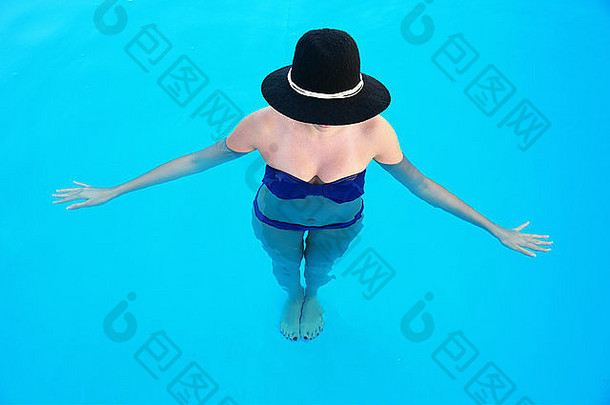 游泳池里站着一个戴帽子的女人的全身肖像