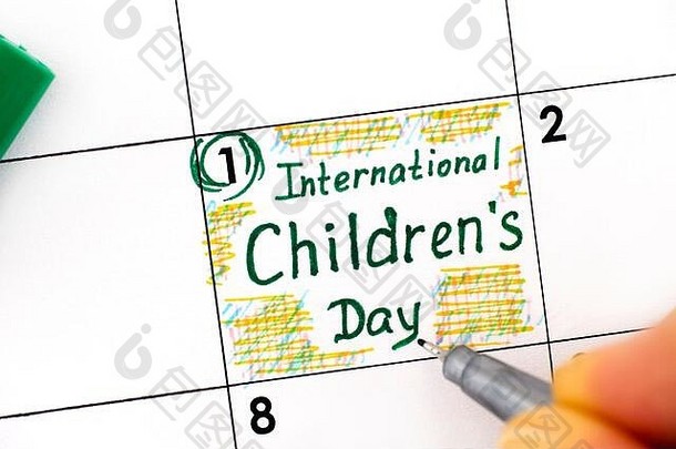 妇女用手指用钢笔书写日历上的国际儿童节提醒。六月一日。