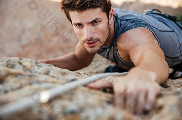 一名男子在陡峭的悬崖上攀岩时伸手抓住