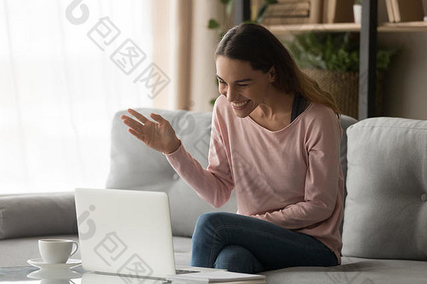 快乐的年轻女子挥手在笔记本电脑上打视频电话