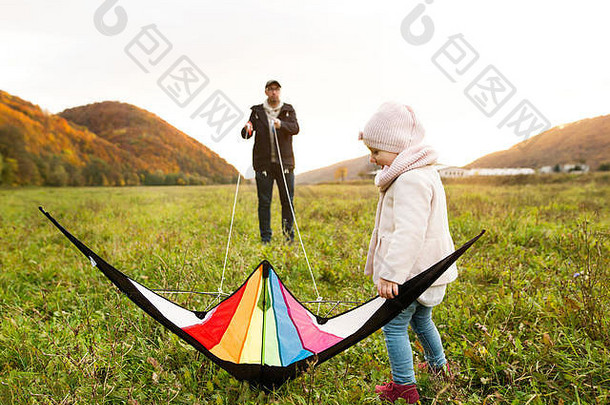 父亲带着带风筝的小女儿。秋天的自然。