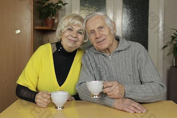 快乐的老爷爷奶奶夫妇坐在家里的桌子上一起喝茶。祖父和祖母微笑着。休闲爱好使人放松。<strong>老年</strong>家庭享受闲暇时光