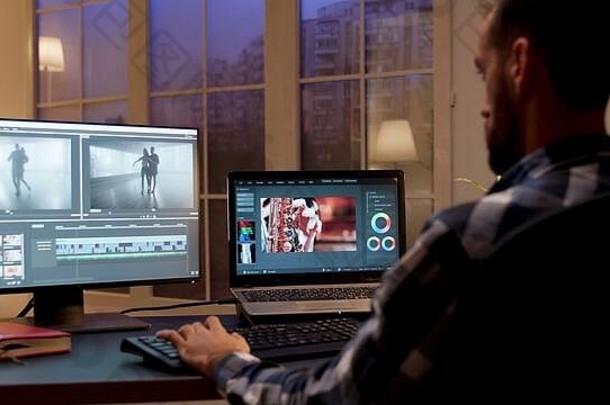 内容创建者夜间在家庭办公室工作的后视图。家庭办公室的视频编辑器。
