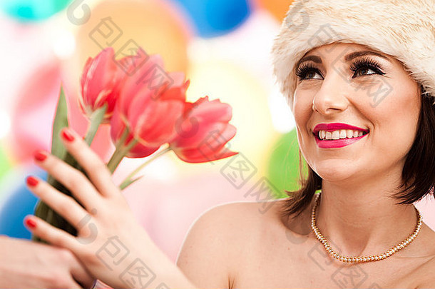可爱的女人微笑着接受红色郁金香。专业化妆。查看同一张照片中的更多图像。