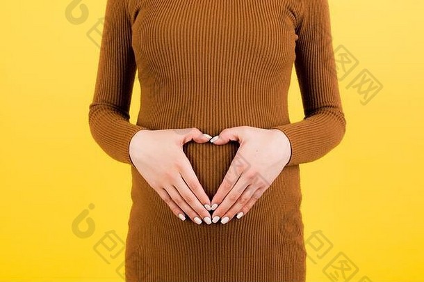 裁剪图像怀孕了女人棕色（的）衣服使心形状手腹部黄色的背景婴儿撞概念复制空间