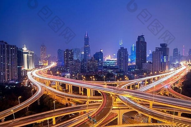 在中国，上海城市交通在繁忙的交叉路口行驶，在夜晚被高大的现代化建筑包围