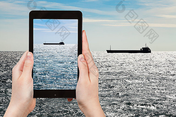 旅游理念-游客在秋夜用手机拍摄黑海中的船只