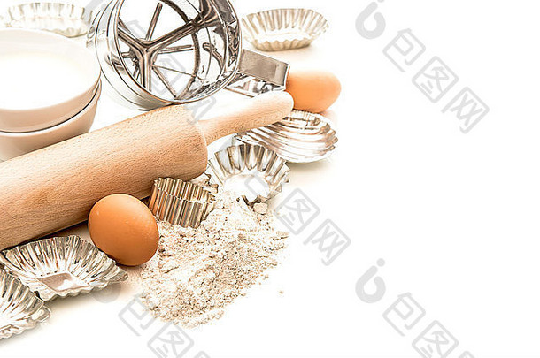 制作面团的烘焙配料和费用。白色背景上的面粉、鸡蛋、擀面杖和饼干切割器