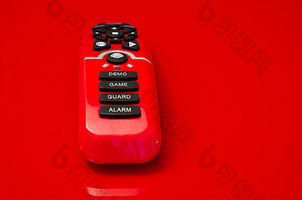 遥控器，用于控制红色背景上的红色闪亮塑料玩具机器人