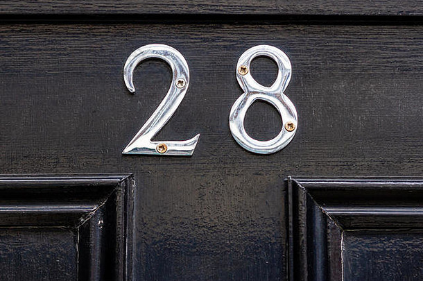 28号房子的黑色木质前门上有28个闪亮的<strong>银色</strong>金属数<strong>字</strong>