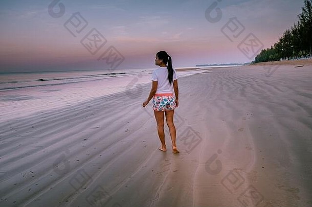 泰国考湖日出时在海滩上行走的妇女