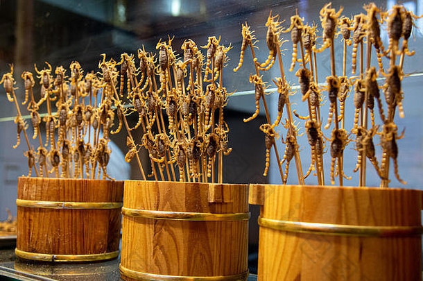 在一根棍子上炸熟美味的蝎子。一种特殊的中国传统街头食品