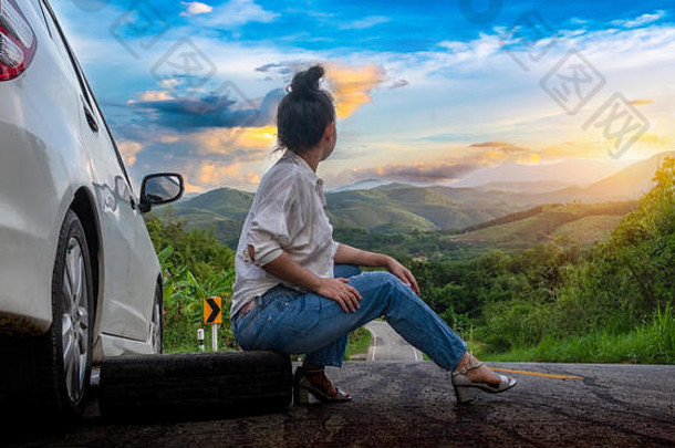 年轻的美丽的夫人坐车调用公共路森林区域山天空背景