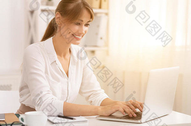 女商人在现代办公室用笔记本电脑打字