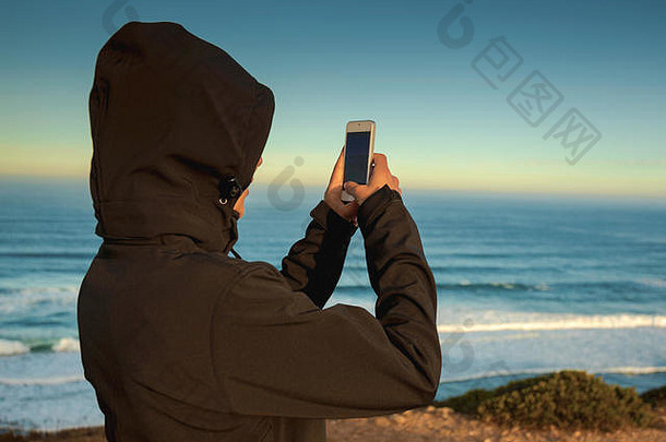 用手机拍海滩照的女人